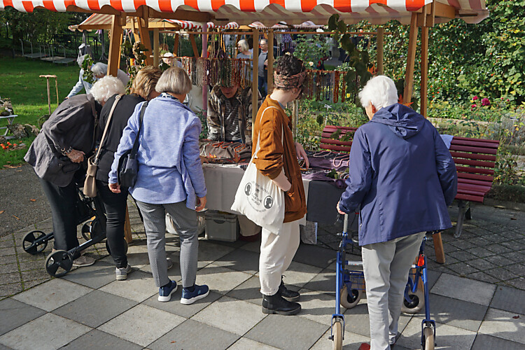 Die Besucherinnen und Besucher des Herbstfests im AZP schauen sich begeistert einen Stand an, der Schmuck verkauft. 